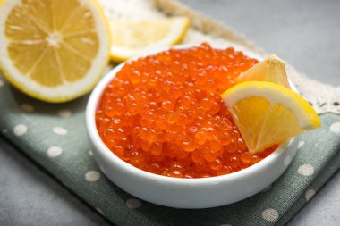 Masadaki beyaz kasede dilimlenmiş limonlu kırmızı havyar. Lüks deniz ürünleri