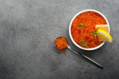 Masadaki beyaz kasede dilimlenmiş limonlu kırmızı havyar. Lüks deniz ürünleri