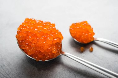 Arka planda kırmızı havyar olan bir kaşık. Aperatif deniz ürünleri