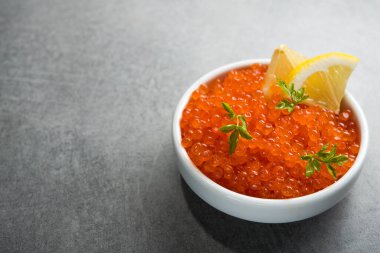 Masadaki beyaz kasede dilimlenmiş limonlu kırmızı havyar. Lüks deniz ürünleri