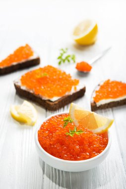 Kırmızı havyarlı sandviçler ve ahşap beyaz masada sarı taze limon. Deniz ürünleri gurmesi.