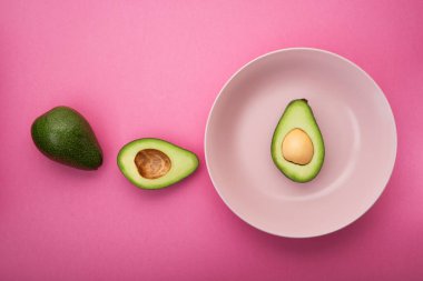 Pembe pastel arka planda taze yeşil avokado. sağlıklı diyet kavramı