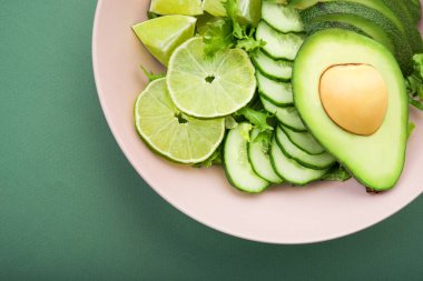 Avokado ile taze salata, yeşil limon ve pastel arka planda salatalık. Diyet konsepti yiyecekler. Üst görünüm