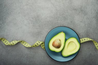 Tabakta taze yeşil avokado, taş masa, mezura ile beslenme zamanı. en üstteki görünüm