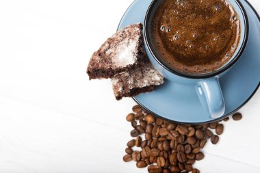 Beyaz ahşap masada çikolatalı kurabiye ile mavi kahve fincanı.