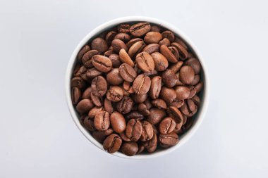 Beyaz arka planda kahve çekirdekleri ile dolu kağıt bardak. İçmeye gitmek ya da götürmek için. en üstteki görünüm