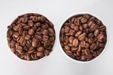 Beyaz arka planda kahve çekirdekleri ile dolu kağıt bardak. İçmeye gitmek ya da götürmek için. en üstteki görünüm