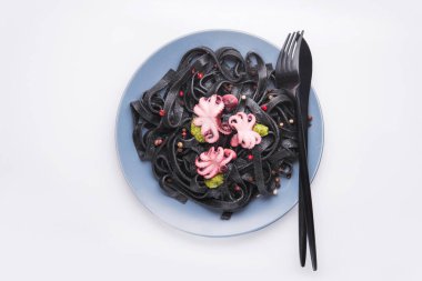 Mürekkepbalığı mürekkepli İtalyan siyah makarna ve beyaza izole edilmiş bir tabakta marine edilmiş ahtapot. Lezzetli Asya deniz ürünleri. Üst görünüm