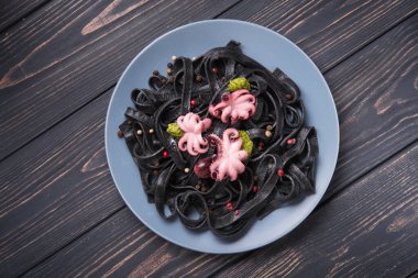 Mürekkep balıklı İtalyan siyah makarna ve masada marine edilmiş ahtapot. Lezzetli Asya deniz ürünleri. Üst görünüm