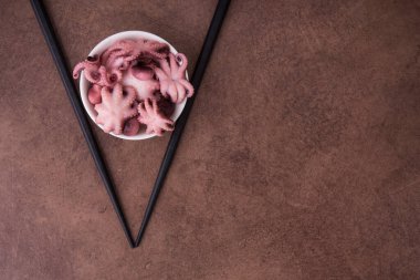 Taş masa zemininde küçük bir ahtapot. Deniz ürünleri yemeği. Üst görünüm.