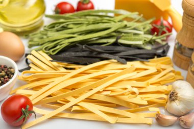 Üç çeşit tagliatelle makarna, klasik, ıspanak ve mürekkep balığı beyaz arka planda izole edilmiş.