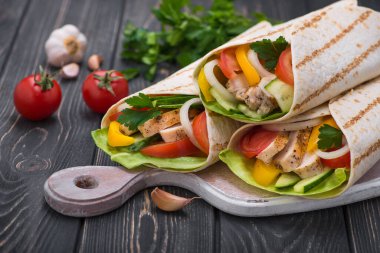 Tortilla, ahşap bir tahtanın üzerinde ızgara tavuk ve taze sebzelerle sarılır. Meksika fast food geçmişi.