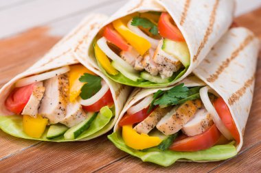 Tortilla ızgara tavuk ve taze sebzelerle ahşap bir masaya sarılır. Meksika fast food geçmişi.