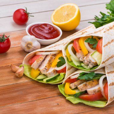 Tortilla ızgara tavuk ve taze sebzelerle ahşap bir masaya sarılır. Meksika fast food geçmişi.