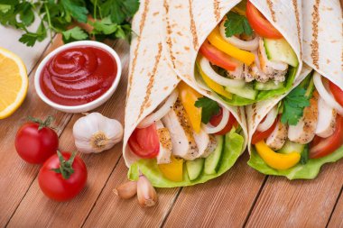 Tortilla ızgara tavuk ve taze sebzelerle ahşap bir masaya sarılır. Meksika fast food geçmişi.