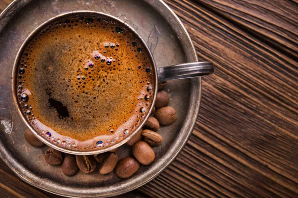 arabic coffee cup with roasted beans on a wooden table. top view