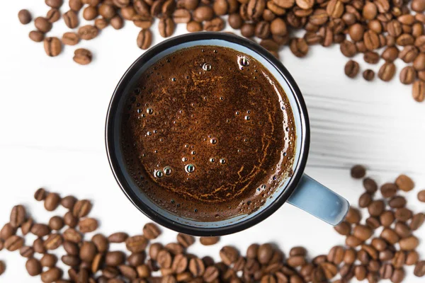 Blue coffee cup with roasted beans on a wooden table. top view