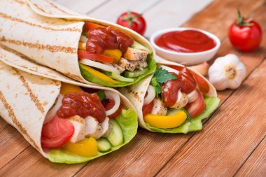 Taco paketleri ızgara tavuk ve taze sebzelerle ahşap bir masada. Meksika fast food geçmişi.
