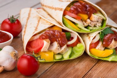 Tortilla ızgara tavuk ve taze sebzelerle ahşap bir masaya sarılır. Meksika fast food geçmişi.