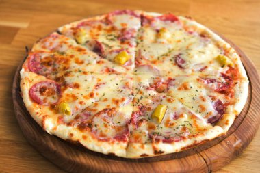 Kafedeki masada peynirli, salamlı ve pepperonili sıcak pizza.