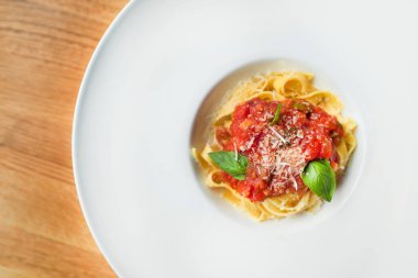 Tahta bir masada peynirli, fesleğenli ve domates soslu tagliatelle makarna. üst yaşam