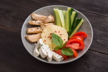 Sebzeli kuskus, tavuk fileto ve ahşap bir masada beyaz peynir. Sağlıklı beslenme geçmişi.