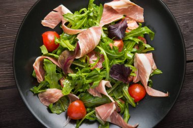 Prosciutto, roka ve domatesli taze salata. diyet yemeği. en üstteki görünüm