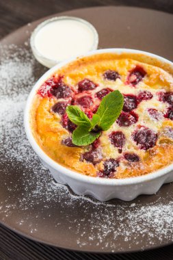 Tahta bir masada kiraz ve yeşil naneli tatlı turta veya güveç.