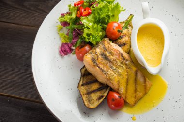 Sebzeli balık bifteği ve beyaz tabakta sos. en üstteki görünüm