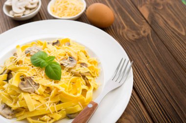 Tahta bir masada peynirli ve fesleğenli İtalyan mantarlı makarna. Lezzetli yemek