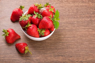 Masadaki kasede taze kırmızı çilek. Tatlı yaz arkaplanı. en üstteki görünüm