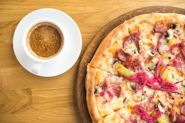 Peynirli İtalyan pizzası, soğan turşusu, mantar ve salam ahşap masa, kahve fincanı, kafede hızlı öğle yemeği. en üstteki görünüm