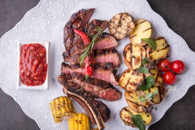 Izgara sebzeli biftek, mısır, patates, tabakta biber. Barbekü yemeği. en üstteki görünüm