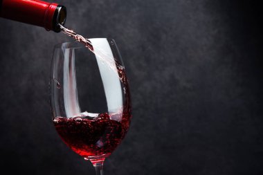 Şarap kadehine dökülen kırmızı şarap, klasik taş arka planda.