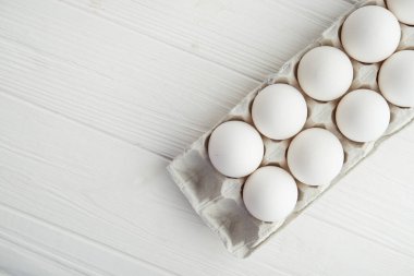 Tahta masadaki tepside çiğ beyaz yumurta. en üstteki görünüm