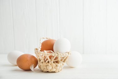 Tahta bir arka planda sepette çiğ yumurta.