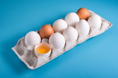 Tepside ev yapımı tavuk yumurtası. Biri kırıldı. Mavi arkaplan.