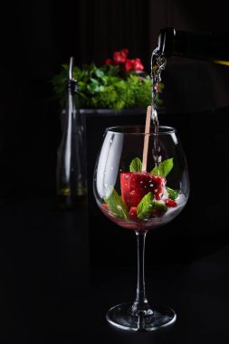 Meyve şerbeti ve naneli bir bardağa köpüklü şarap dök restorandaki karanlık bir masanın üzerine.