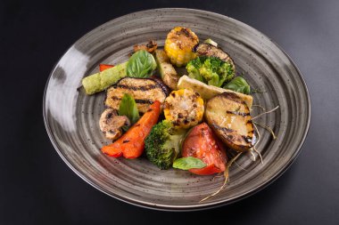 Tabakta ızgara sebze ve fesleğen yaprağı. koyu arkaplan