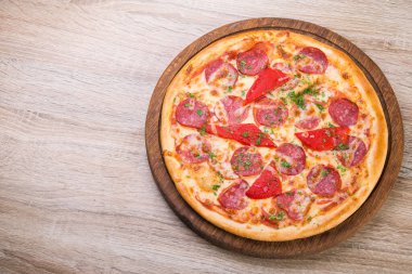 Ahşap bir masada salamlı ve kırmızı biberli baharatlı lezzetli pizza. en üstteki görünüm