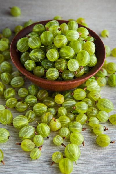 green fresh gooseberry berry in a bowl on wooden table. ripe fruit food