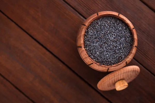 Wood barrel full of poppy seeds on table. top view