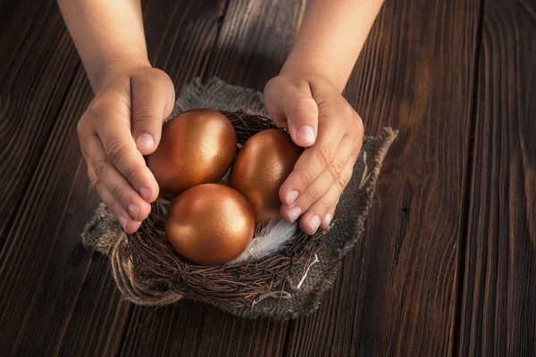 Bambino Protegge Attentamente Uova Oro Nel Nido Tavolo Legno Concetto — Foto Stock