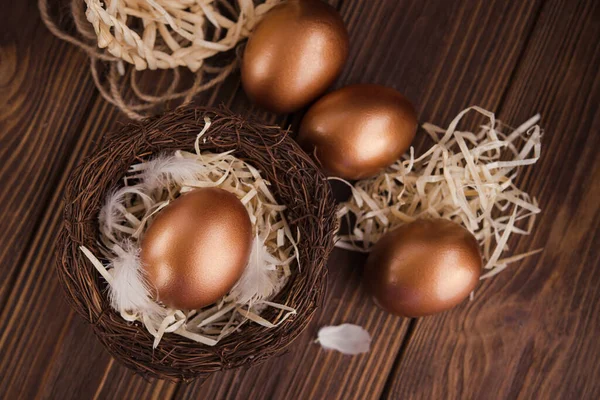 Golden eggs in the nest on a wooden table. concept of wealth and luck. top view