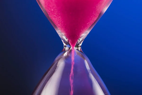 青の背景に砂時計と明るいピンクの砂 — ストック写真