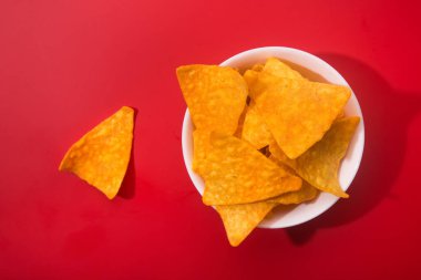 Kırmızı arka planda altın nacho cipsleri. Düz Yat. Çıtır Meksika yemeği..