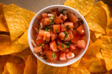 El işi karton bir arka planda altın cips ve domates sosu. Meksika atıştırması. düz yatış, üst görünüm