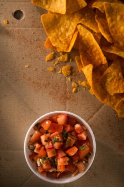 El işi karton bir arka planda altın cips ve domates sosu. Meksika atıştırması. düz yatış, üst görünüm