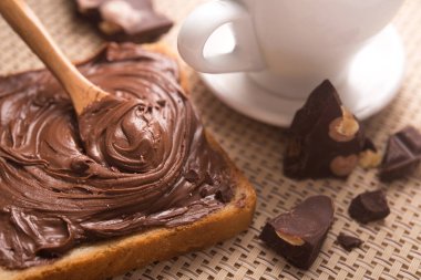 Çikolatalı ekmeğin tatlı kahvaltısı ve sabah masasında bir fincan kahve.