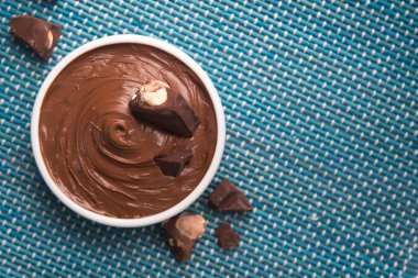 Lezzetli erimiş çikolatalı kase mavi ahşap masada.